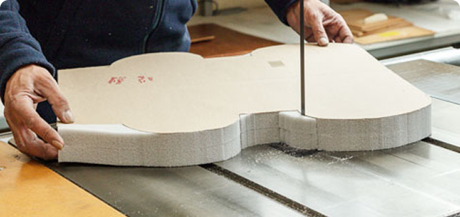 Person cutting a custom-shaped foam material with a bandsaw
