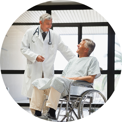 Smiling doctor talking to an older male patient sitting in a wheelchair inside a hospital