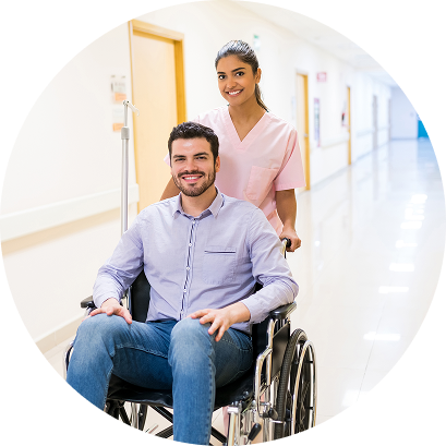 Smiling nurse pushing a young male patient in a wheelchair down a hospital corridor
