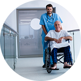 Smiling healthcare worker pushing an older male patient in a wheelchair down a hospital hallway