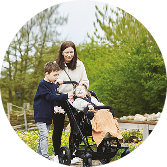 Woman with two children outdoors, one child sitting in a wheelchair stroller
